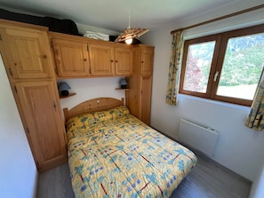 Une chambre à coucher avec un lit, des armoires en bois, une fenêtre et un radiateur.