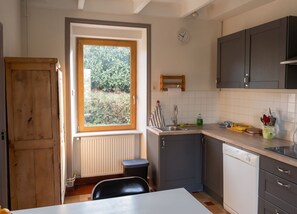 A compact kitchen with a window, a sink, cabinets, and a dishwasher.