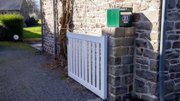 A stone building with a white gate, a mailbox, and a clear sky.