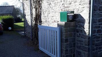 A stone building with a white gate, a mailbox, and a green box on the wall.