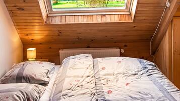 Een slaapkamer met dakraam, een bed met bloemenbedrukking en uitzicht op een park.