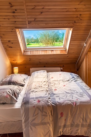 Een slaapkamer met dakraam, een bed met bloemenbedrukking en uitzicht op een park.