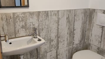 A bathroom with a white sink, a toilet, and a wooden basket on the floor.