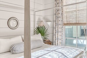 Une chambre à coucher avec un lit, une table de chevet, une lampe, une plante en pot et une fenêtre avec des rideaux.