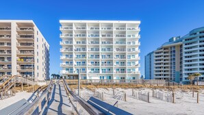 A multi-story hotel with balconies, a sandy beach in the foreground, and a clear blue sky. - Beachfront Beauty - Practically New 1BR Condo! Gulf Front At Perdido Skye (Pensacola)