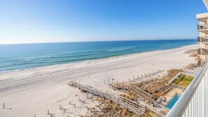 A beach view from a balcony with a pool and a wooden walkway leading to the beach. - Beachfront Beauty - Practically New 1BR Condo! Gulf Front At Perdido Skye (Pensacola)