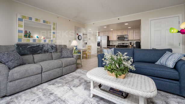 A living room with a grey sofa, a blue sofa, a coffee table with a plant, and a kitchen in the background. - 2-A DELANO CONDO - OCEAN BLOCK-1406 Coastal Hwy, Dewey Beach- DOG FRIENDLY! (Dewey Beach)
