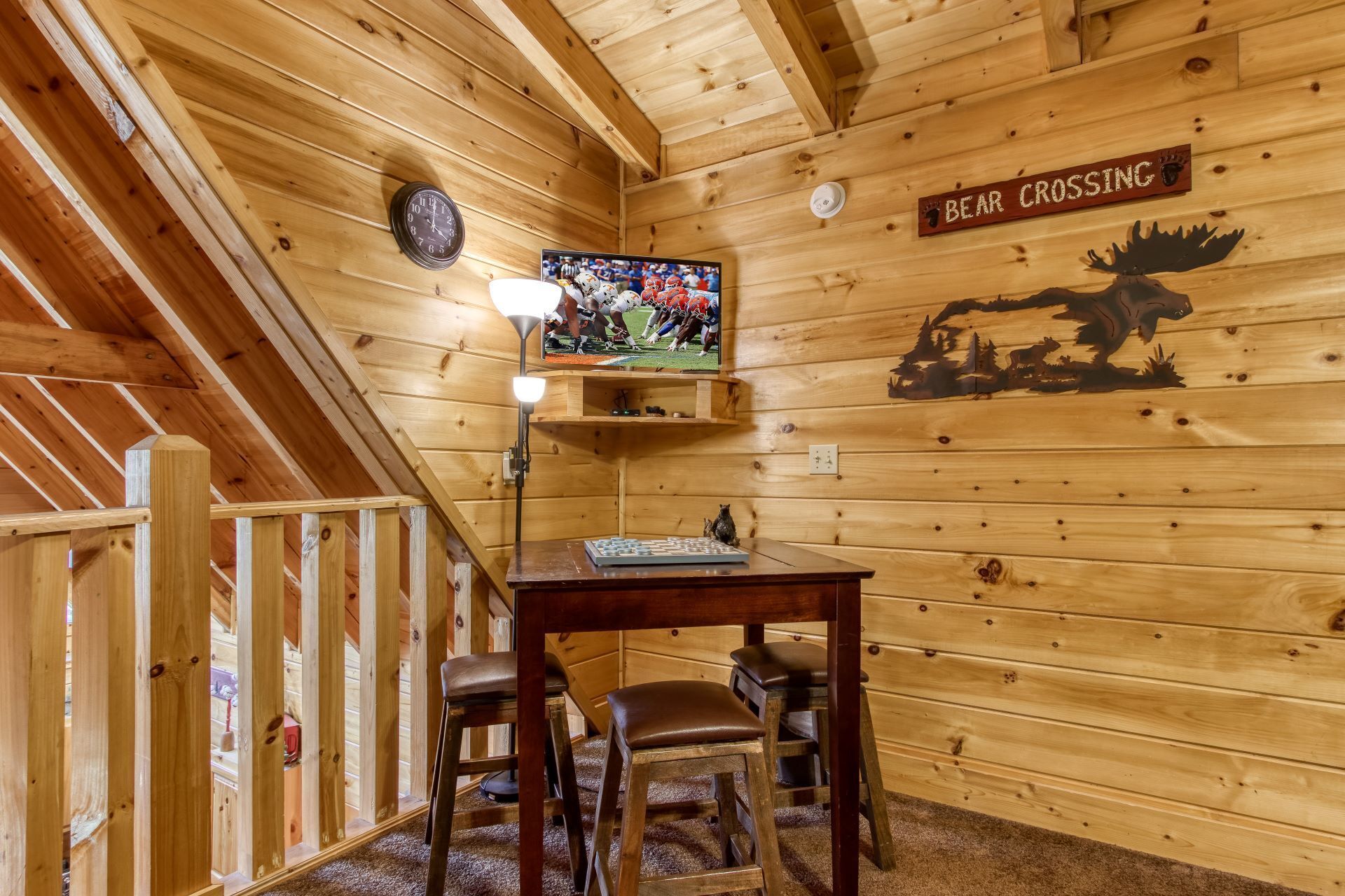 A wooden interior with a television, a bear crossing sign, and a moose carving.