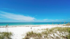 Een strand met wit zand en helderblauw water.