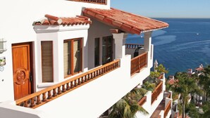 A coastal building with a balcony, white walls, and a red-tiled roof.