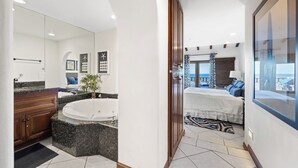 A modern bathroom with a large bathtub, a separate shower area, and a vanity with a granite countertop.