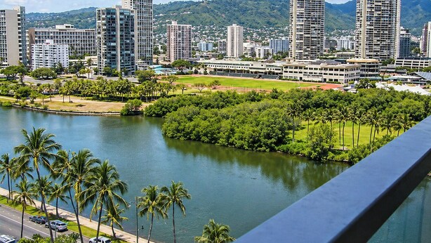 A cityscape with high-rise buildings, a river, and a park with palm trees. - Clean studio at the heart of Waikiki!! (Honolulu)