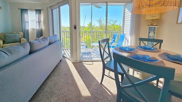 Un salon avec un canapé, une table à manger avec des chaises et un balcon doté d’une balustrade.