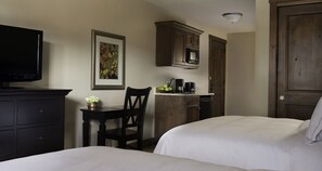A hotel room with two beds, a television, a desk with a chair, a microwave, and a coffee maker.
