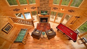 Una cabaña de madera con mesa de fútbol, mesa de billar y chimenea.