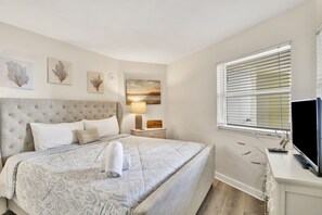 Una camera da letto ordinata con un letto grande, un comodino con una lampada e una televisione su un mobile.