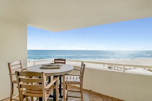 Un balcone con un tavolo rotondo e sedie, vista sulla spiaggia e sull'oceano.