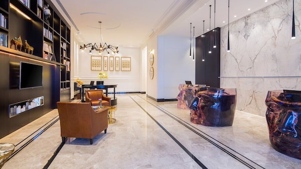A modern lobby with marble flooring, a piano, leather armchairs, a bookshelf, and a TV. - The Bamboo Hotel Hong Qiao Airport (Shanghai)