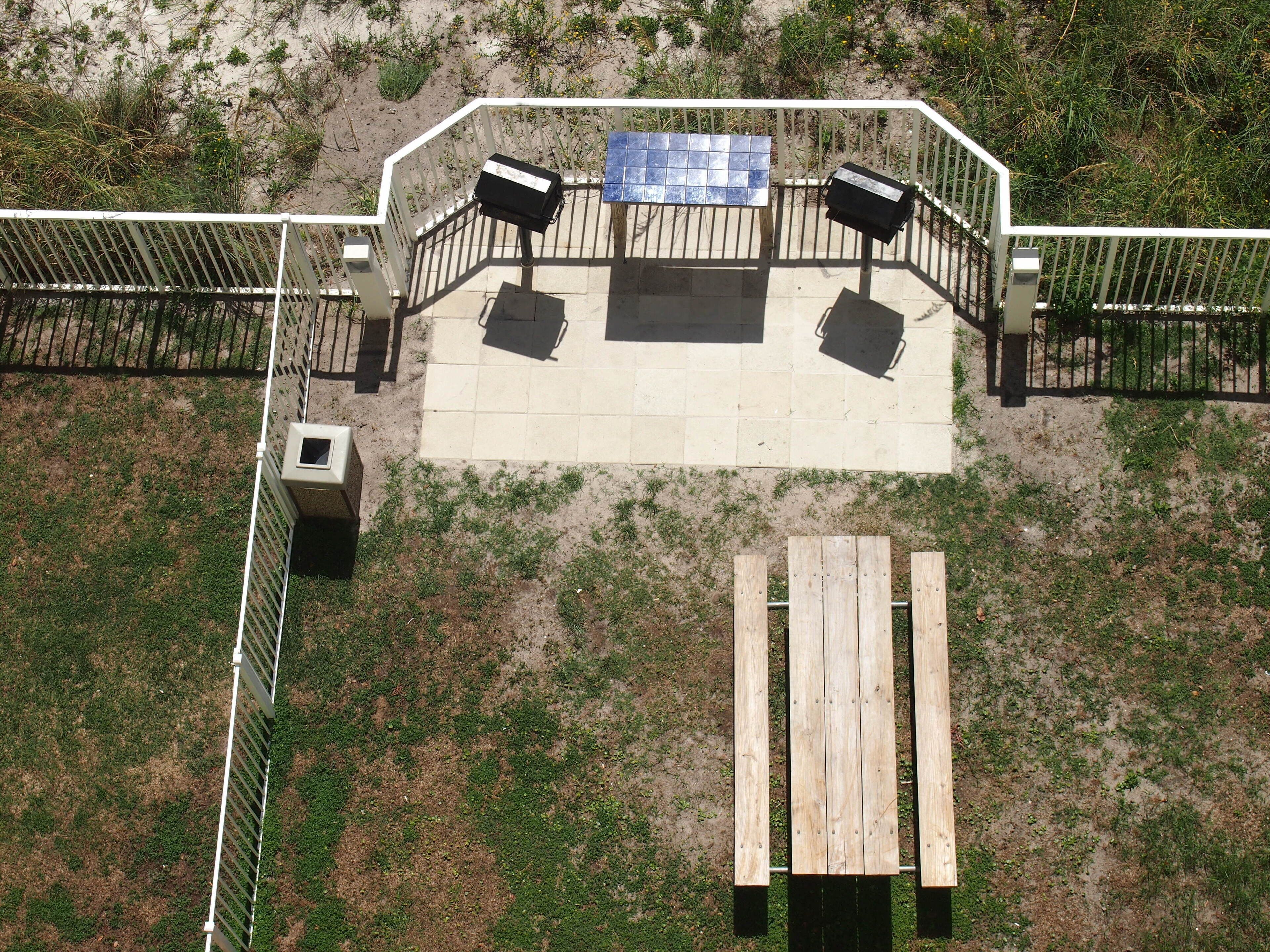 A fenced outdoor area with a picnic table and benches, surrounded by a white railing.