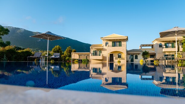 Una piscina cristalina con el reflejo de edificios y una montaña al fondo.