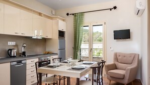Una cocina moderna con comedor, que incluye una mesa puesta para cuatro personas, un sofá y un televisor montado en la pared.