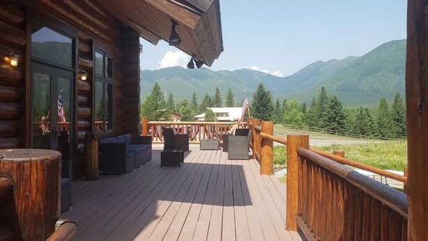 A wooden deck with outdoor seating and a view of mountains.