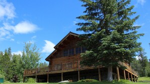 A large log cabin with a balcony and a large tree in front.
