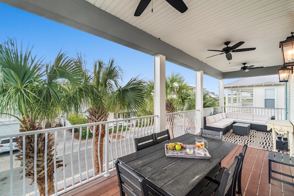 A covered outdoor patio with a dining table, chairs, and a sofa.