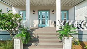 A porch with a wooden railing, a blue door, and a white wall. - Forever Summer: Discover Your Happy Place! (Rosemary Beach)