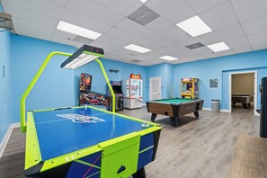 A recreational room with a foosball table, pool table, and arcade games.
