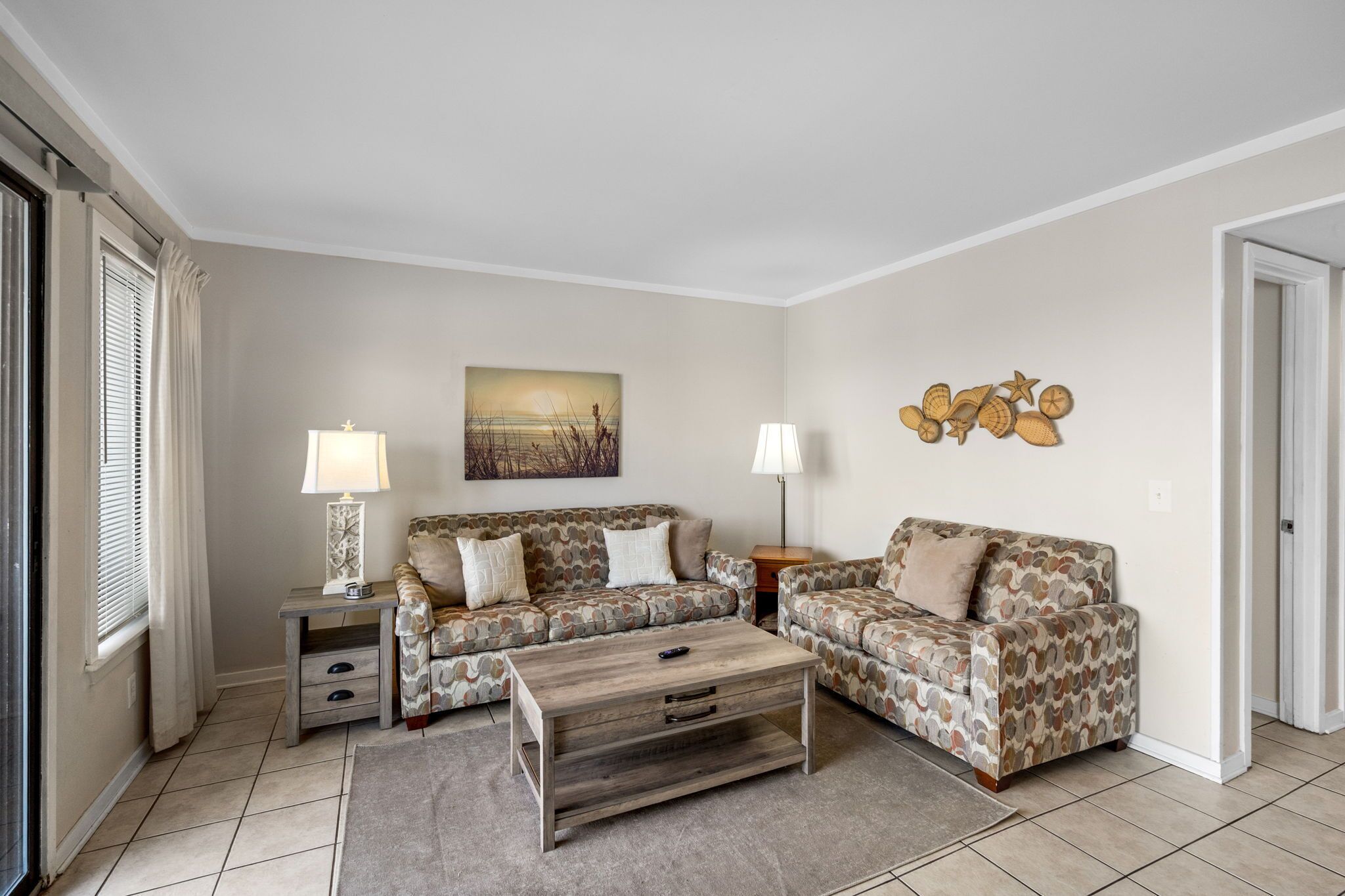 A living room with two patterned sofas, a wooden coffee table, and two lamps.