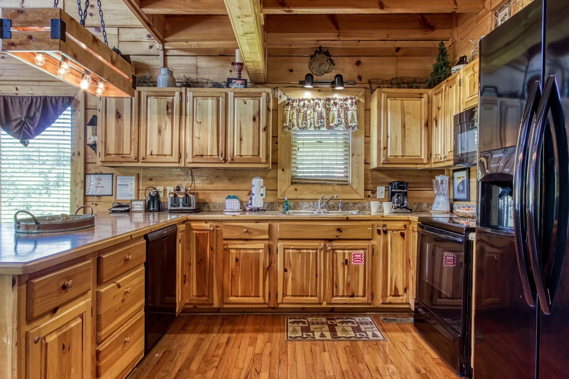 Cucina in stile baita con isola centrale, mobili in legno, frigorifero e diversi elettrodomestici.