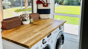 Un cuarto de lavandería con lavadora, encimera de madera, cestos de mimbre y vistas al exterior.