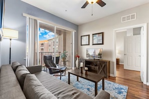 A modern living room with a sofa, armchair, coffee table, and a ceiling fan.