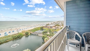 Ein Balkon mit Blick auf einen Strand, ein kleines Gewässer und einen Steg.