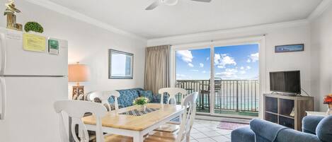Una habitación con una mesa de comedor, sillas, un sofá, un televisor y un balcón con vistas.
