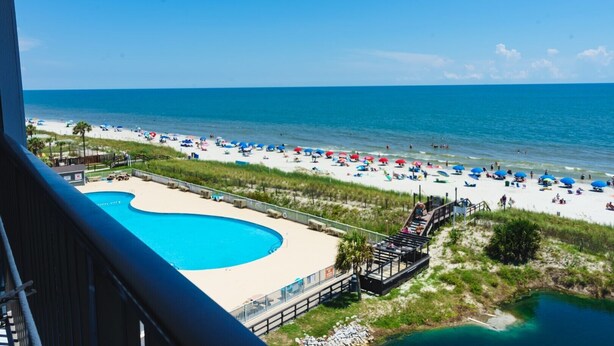 Ein Strandresort mit Schwimmbad, Strandliegen und einer Promenade.