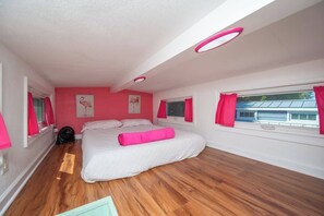 A bedroom with a large bed, pink curtains, and a window with a view of a building.