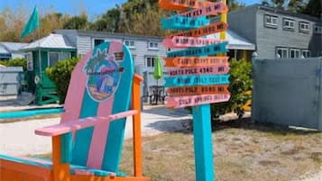 A colorful signpost with destinations and distances, a beach chair, and a building in the background.