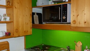 A kitchen with wooden cabinets, a microwave, a stove, and a sink. - Duplex 2-room, sleeps 6, ski-in/ski-out, Arc 1800, pets allowed (Les Arcs 1800)