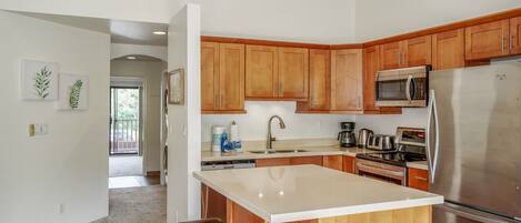 A modern kitchen with wooden cabinets, stainless steel appliances, and a central island with stools.