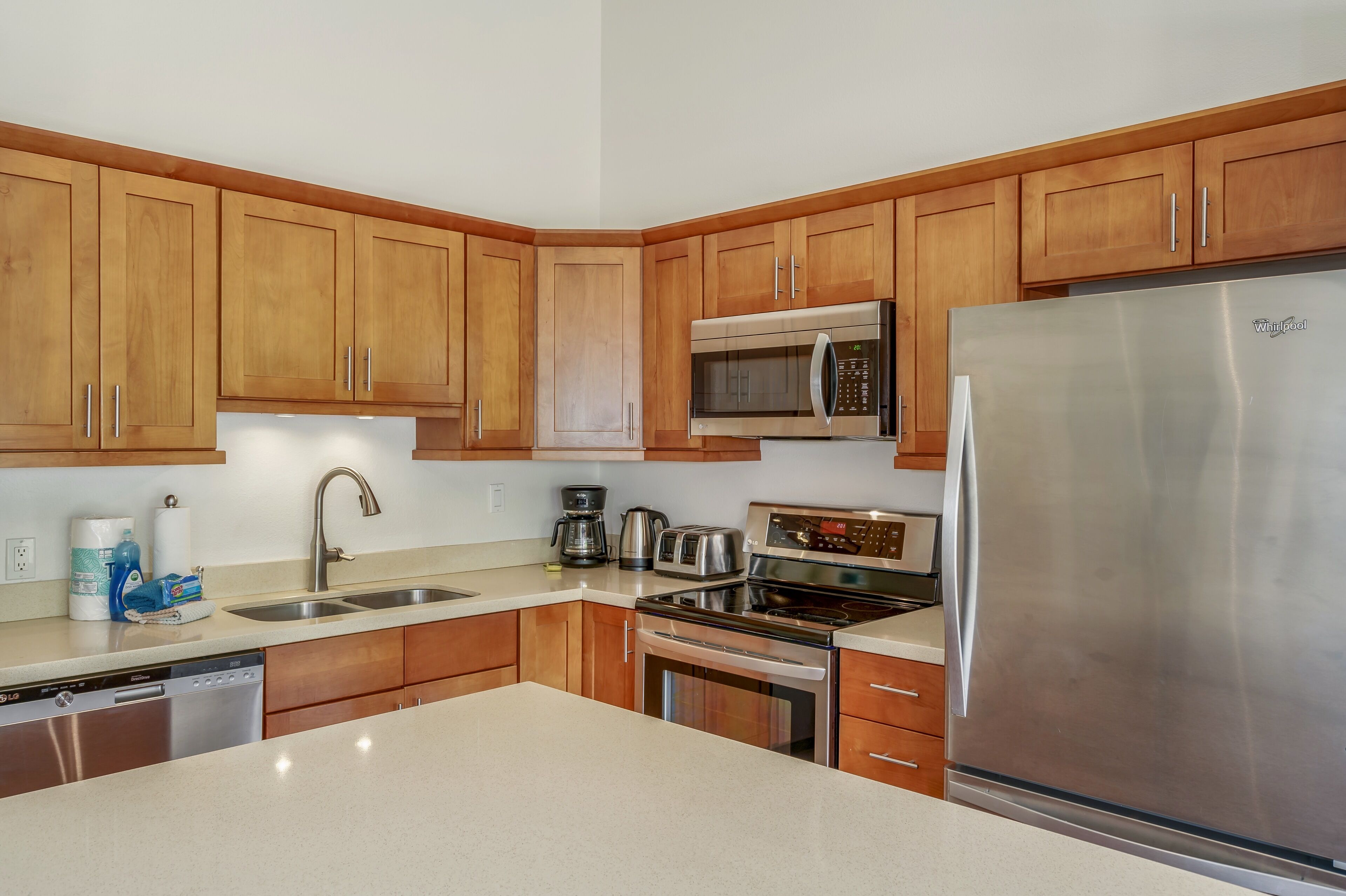 A modern kitchen with wooden cabinets, stainless steel appliances, and a granite countertop.