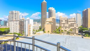 Une vue urbaine avec de hauts immeubles, un ciel dégagé et une terrasse sur le toit.