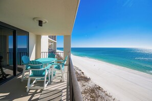 A balcony with a table and chairs overlooking a beach.
