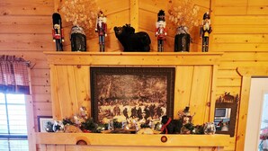 A cozy fireplace with a bear figurine, nutcracker figurines, and a framed picture above it.