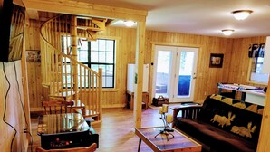 A wooden interior with a spiral staircase, a dining area, a sofa, and a hockey-themed wall.