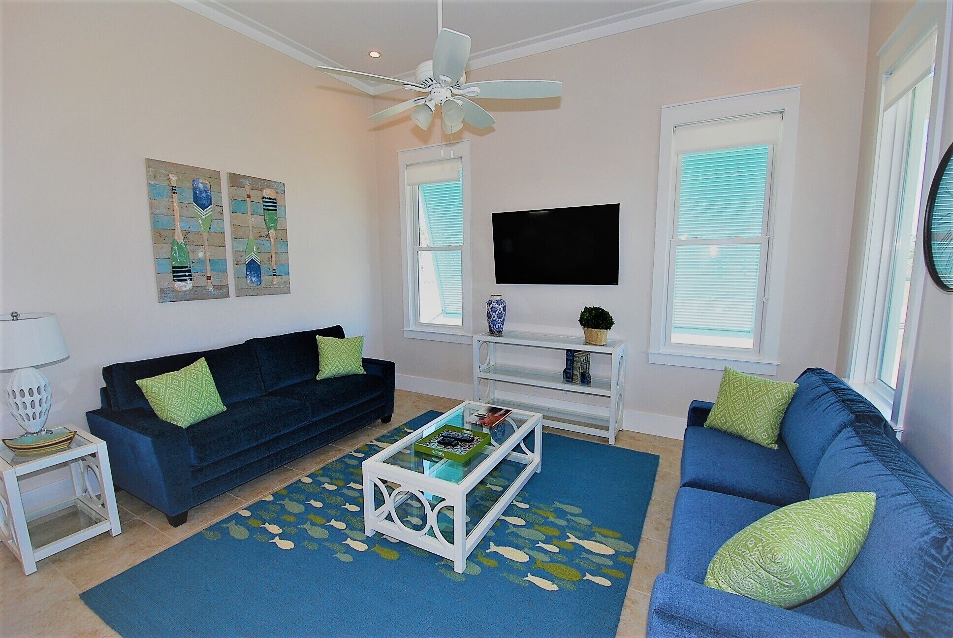A living room with two dark blue sofas, a white coffee table, and a ceiling fan.