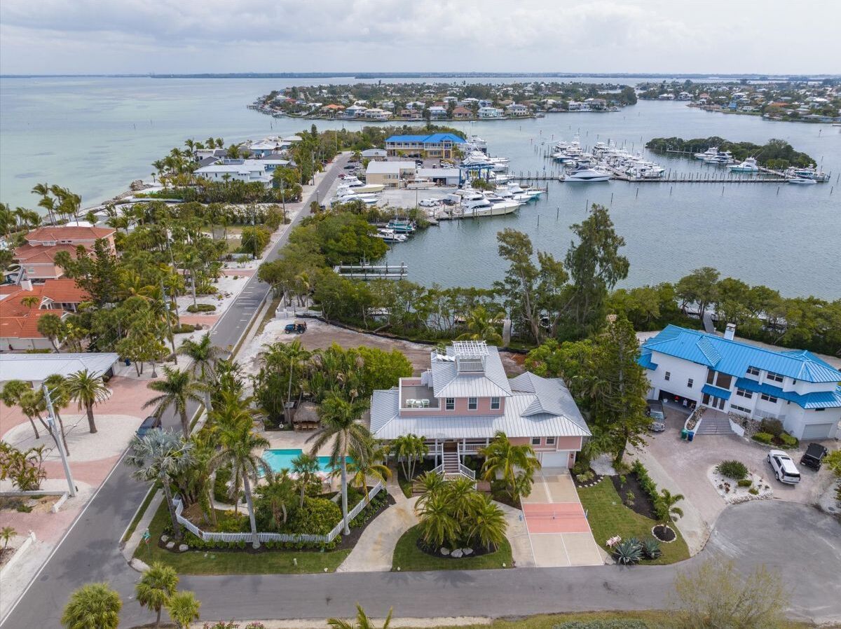 A coastal property with a swimming pool, a dock with boats, and a marina.