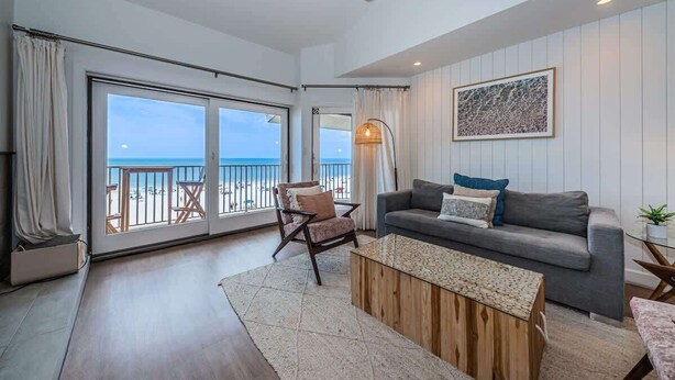 A spacious living area with a balcony, a ceiling fan, a sofa, and a coffee table. - A17 Villas of Clearwater Beach Gulf-Front Condo (Clearwater Beach)
