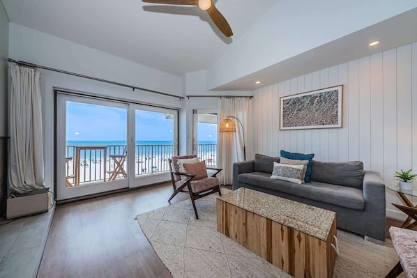 A spacious living area with a balcony, a ceiling fan, a sofa, and a coffee table.